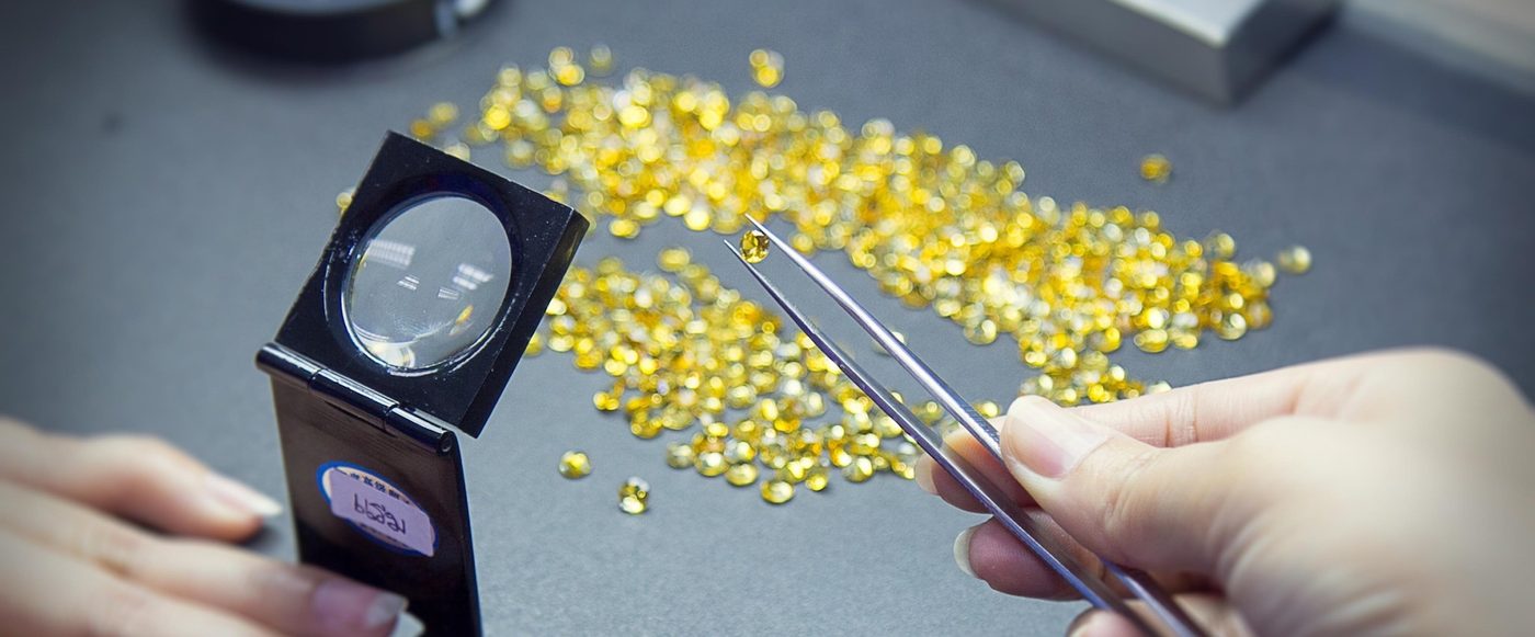 Loose synthetic stones being sorted with a loupe and tweezers